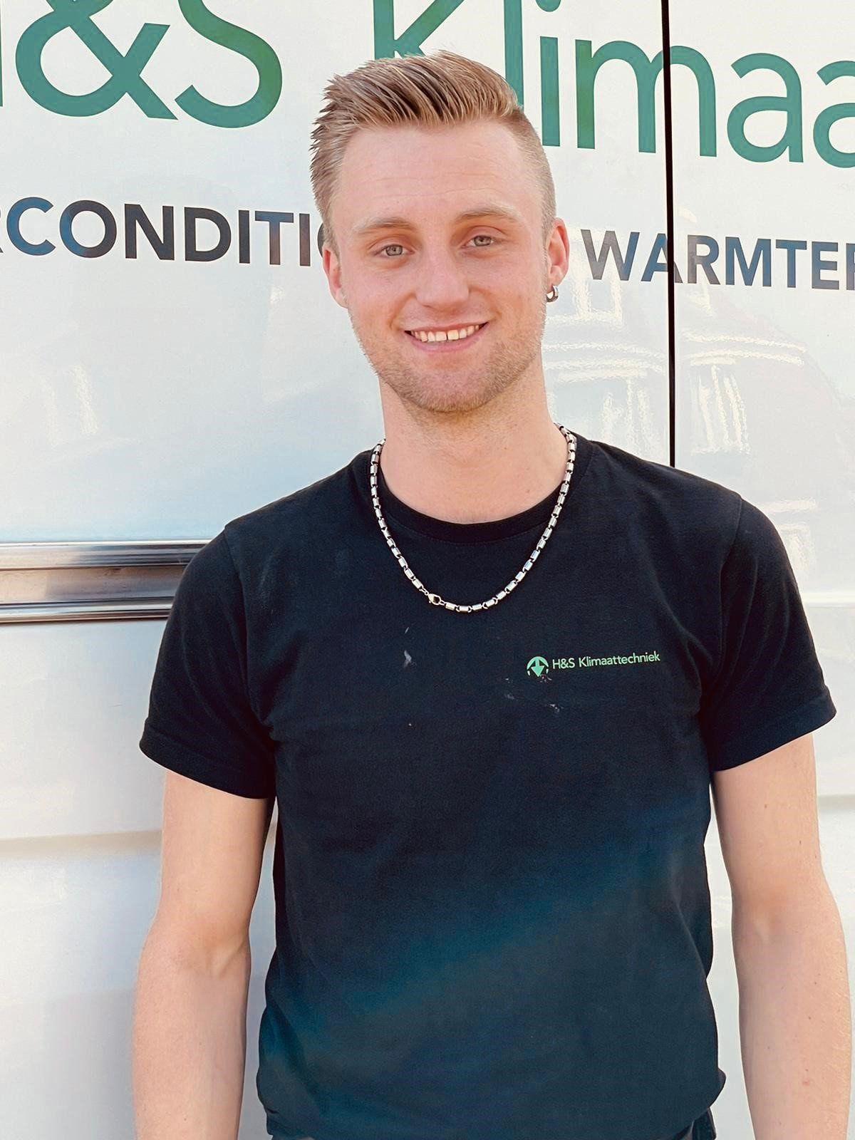 Een man in een zwart shirt staat voor een bord met de tekst klimaa