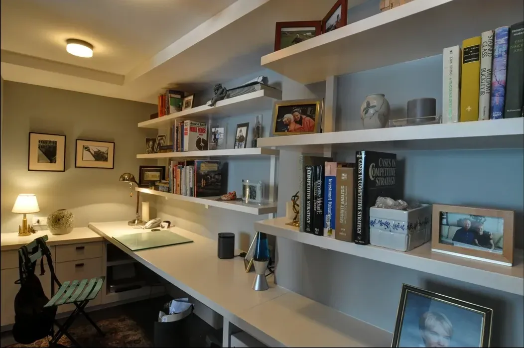 A room with a desk and shelves filled with books and pictures