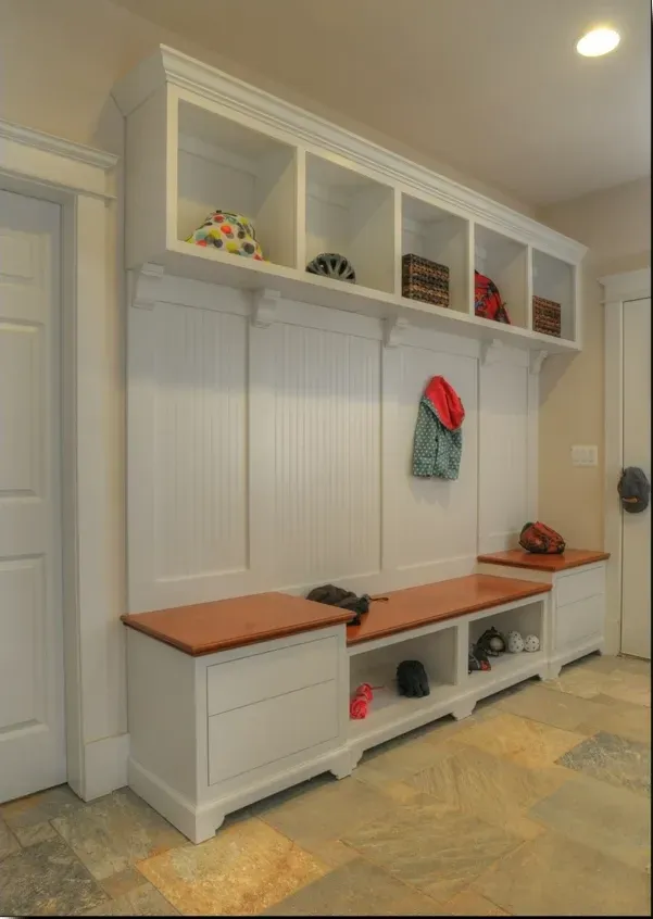 A hallway with white cabinets and a wooden bench
