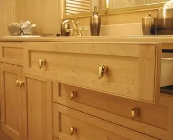 A bathroom with a sink , cabinets , drawers and a mirror.