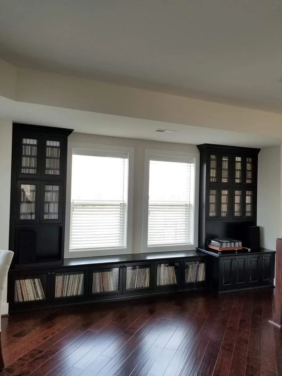 A living room with hardwood floors and black cabinets