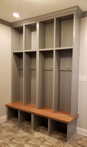 A locker room with a bench and shelves in a house.