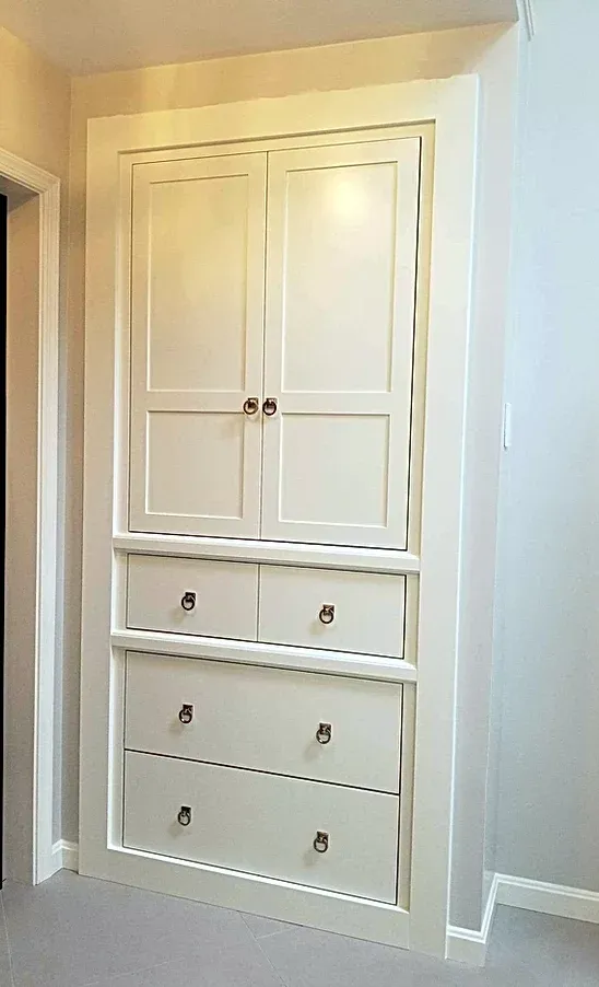 A white cabinet with drawers and shelves in a hallway.