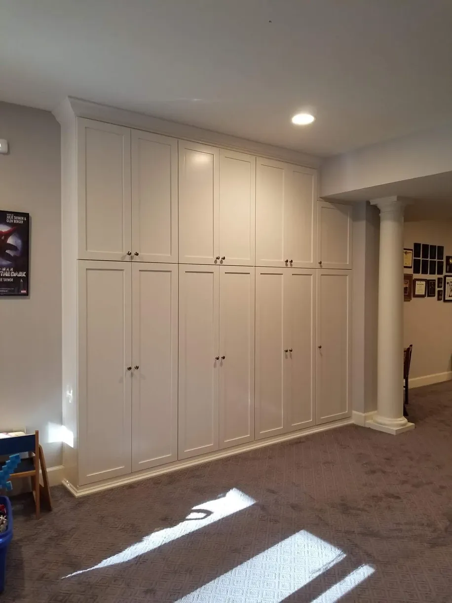 A room with a lot of white cabinets on the wall