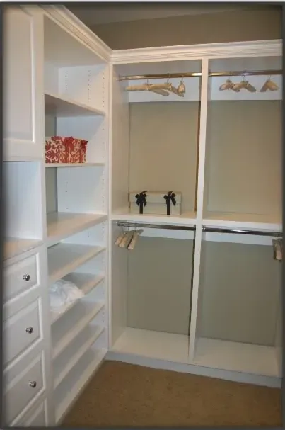 A walk in closet with white shelves and drawers