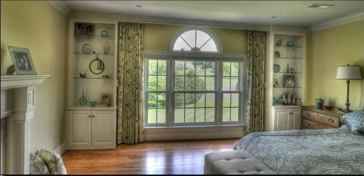 A bedroom with a large window and a bed
