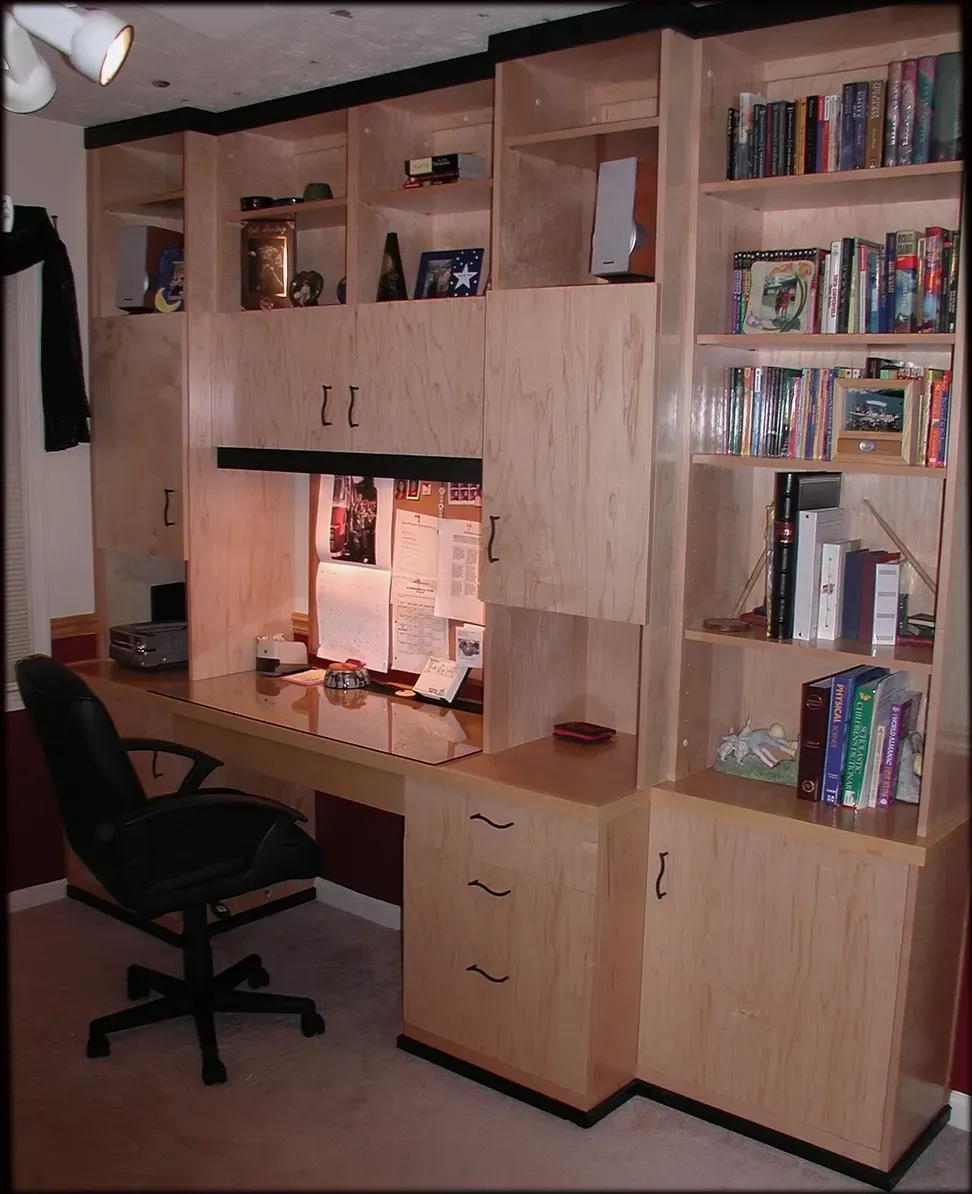 A desk with a chair and a shelf with books on it