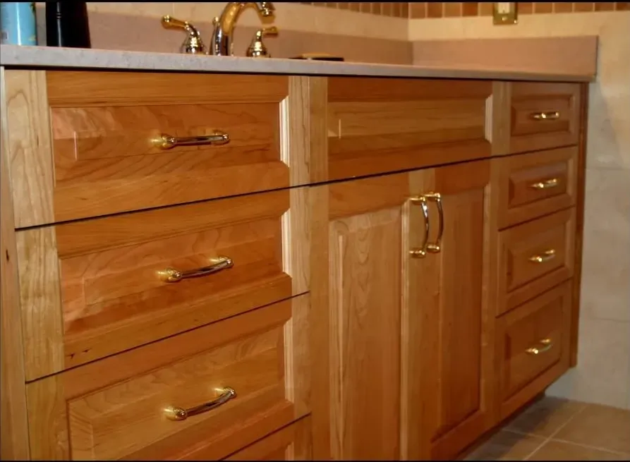 A bathroom vanity with wooden drawers and brass handles