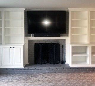 A living room with a fireplace , shelves , and a flat screen tv.