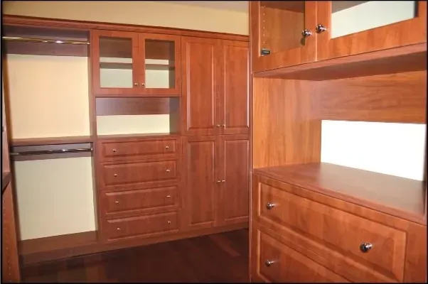 A walk in closet with wooden cabinets and drawers