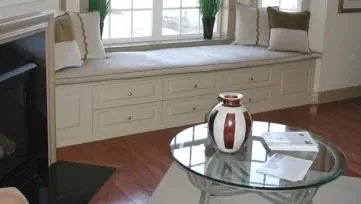 A living room with a window seat and a glass coffee table