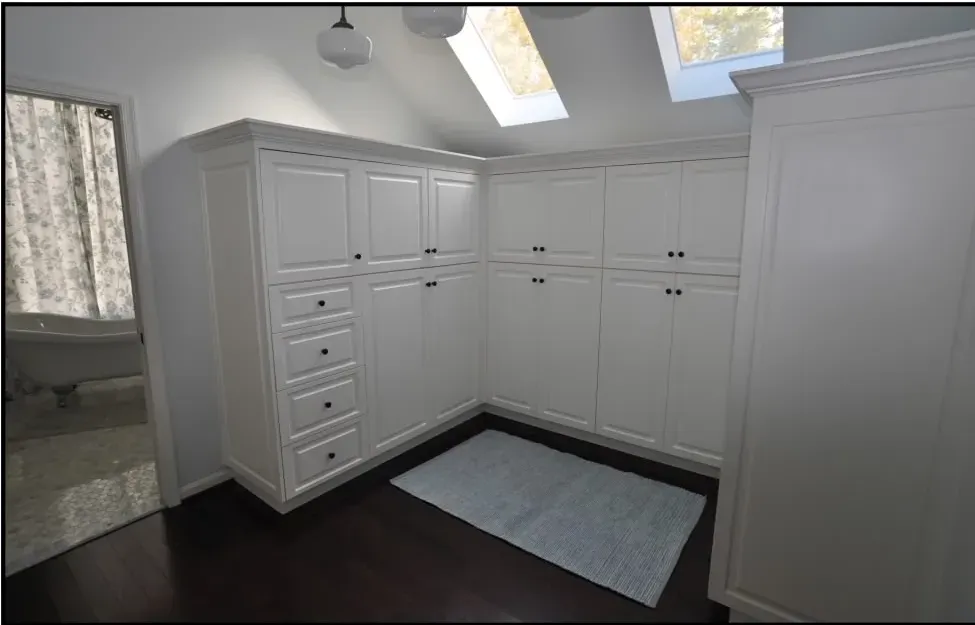 A walk in closet with lots of white cabinets and drawers