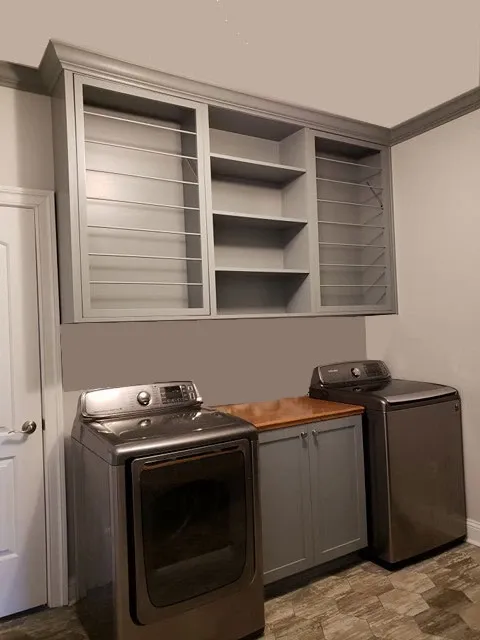 A laundry room with a washer and dryer and shelves above them.