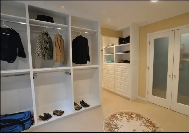 A walk in closet with clothes and shoes on shelves