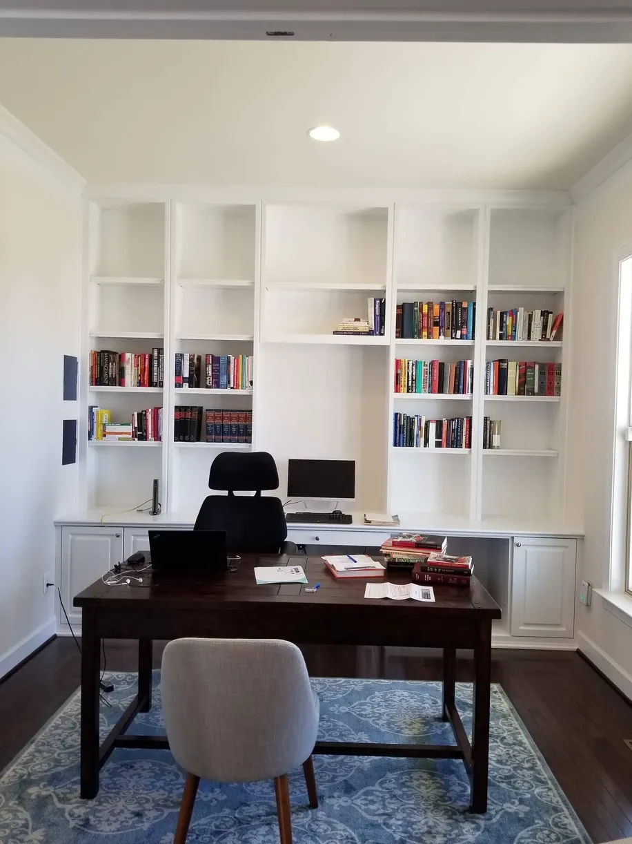 A home office with a desk and chair surrounded by bookshelves