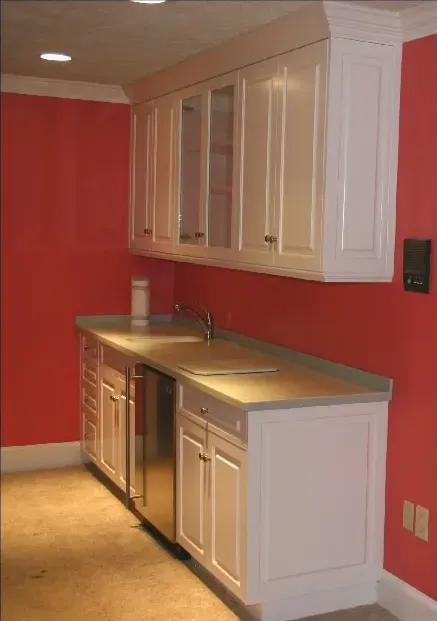 A kitchen with red walls and white cabinets