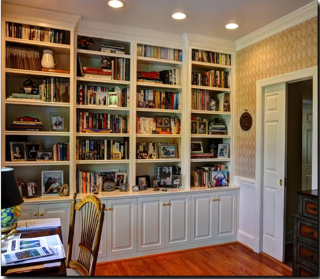 A room with lots of books and pictures on the shelves