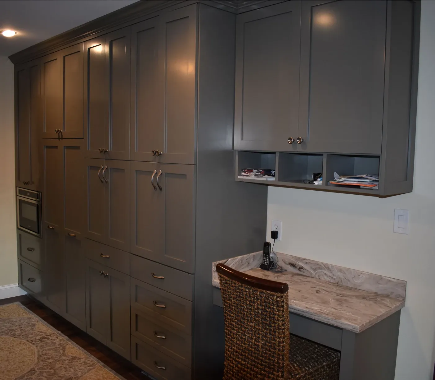 A wicker chair sits next to a desk in a kitchen