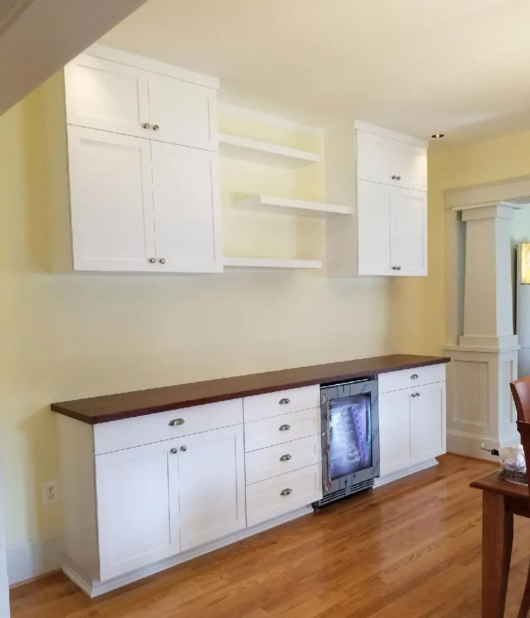 A kitchen with white cabinets and a flat screen tv