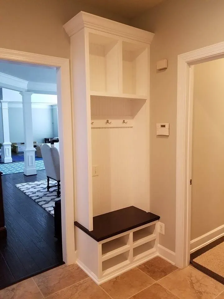 A hallway with a white cabinet and a bench in it.