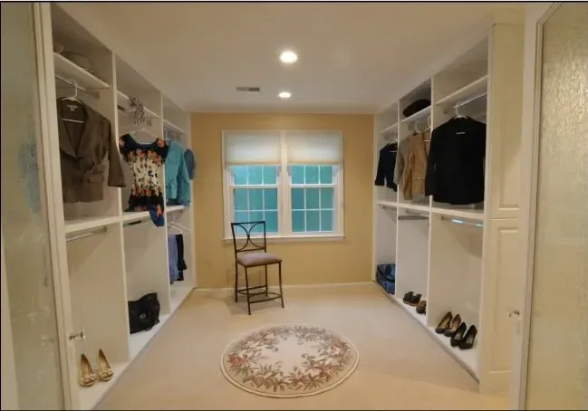 A large walk in closet with a chair in the middle