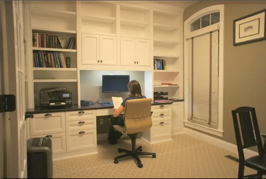 A woman sits at a desk in a home office