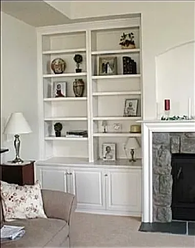 A living room with white shelves and a fireplace