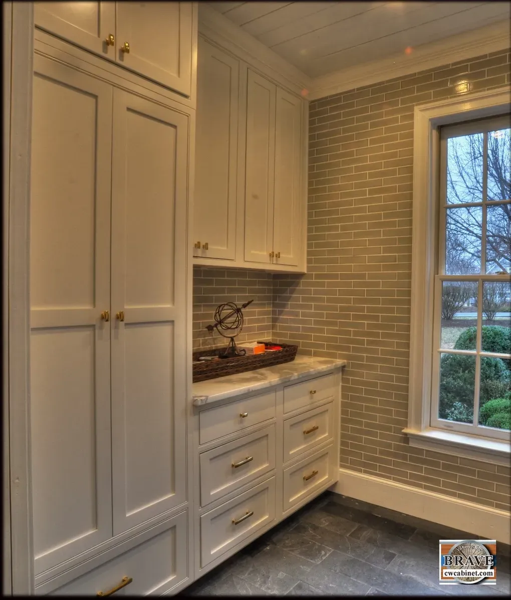 A kitchen with white cabinets and drawers and a window