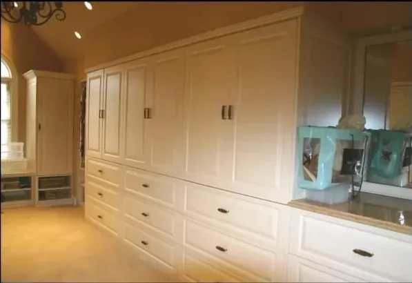 A room with lots of cabinets and drawers and a mirror