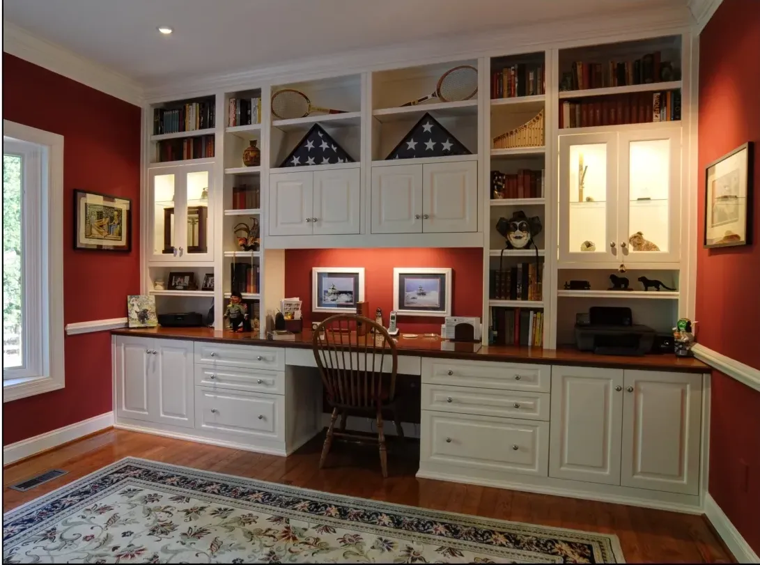 A home office with red walls and white cabinets
