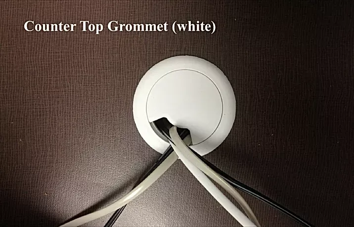 A white counter top grommet with wires coming out of it
