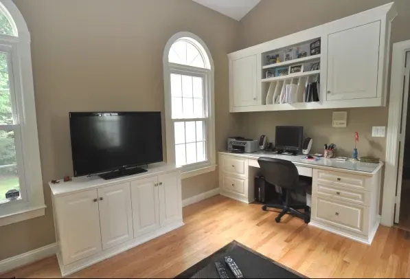 A home office with a desk and a flat screen tv