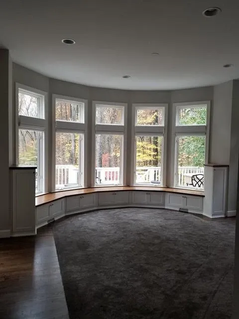 A living room with a curved window seat and a lot of windows.