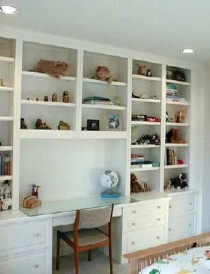 A bedroom with a desk , chair , shelves and a crib.