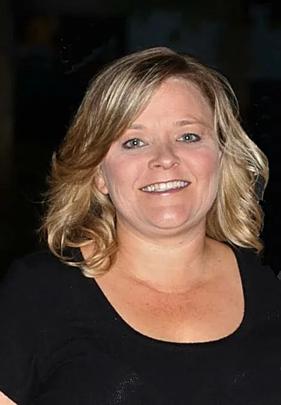 A woman in a black shirt is smiling for the camera.