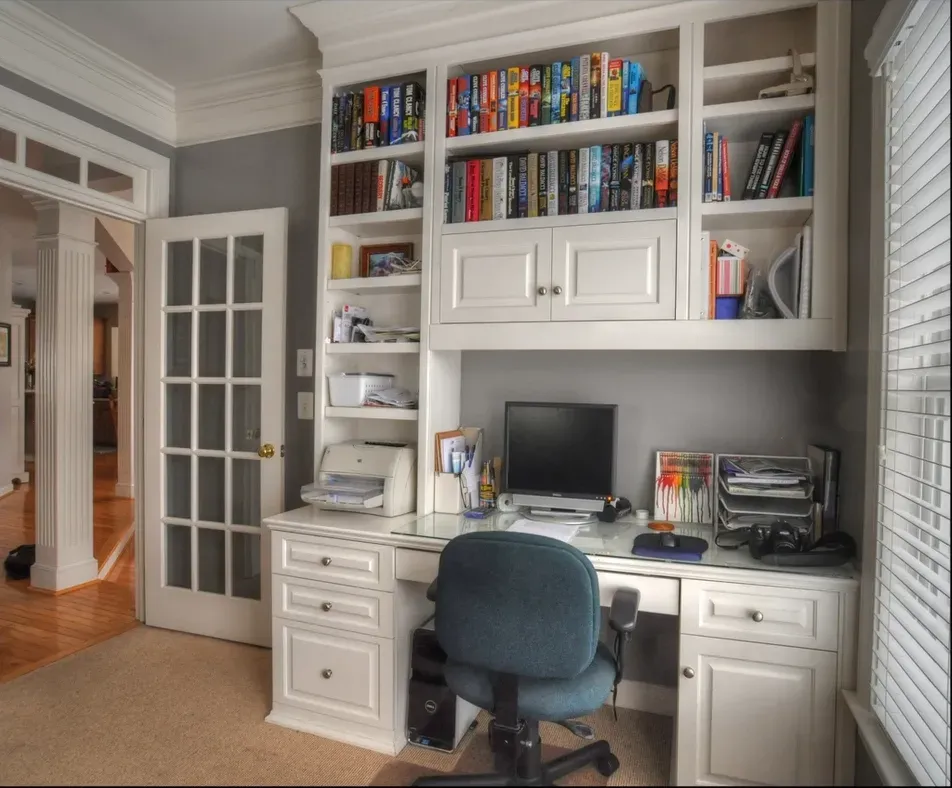 A desk with a computer and bookshelves behind it