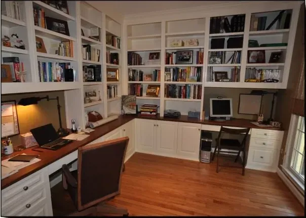A home office with lots of bookshelves and desks