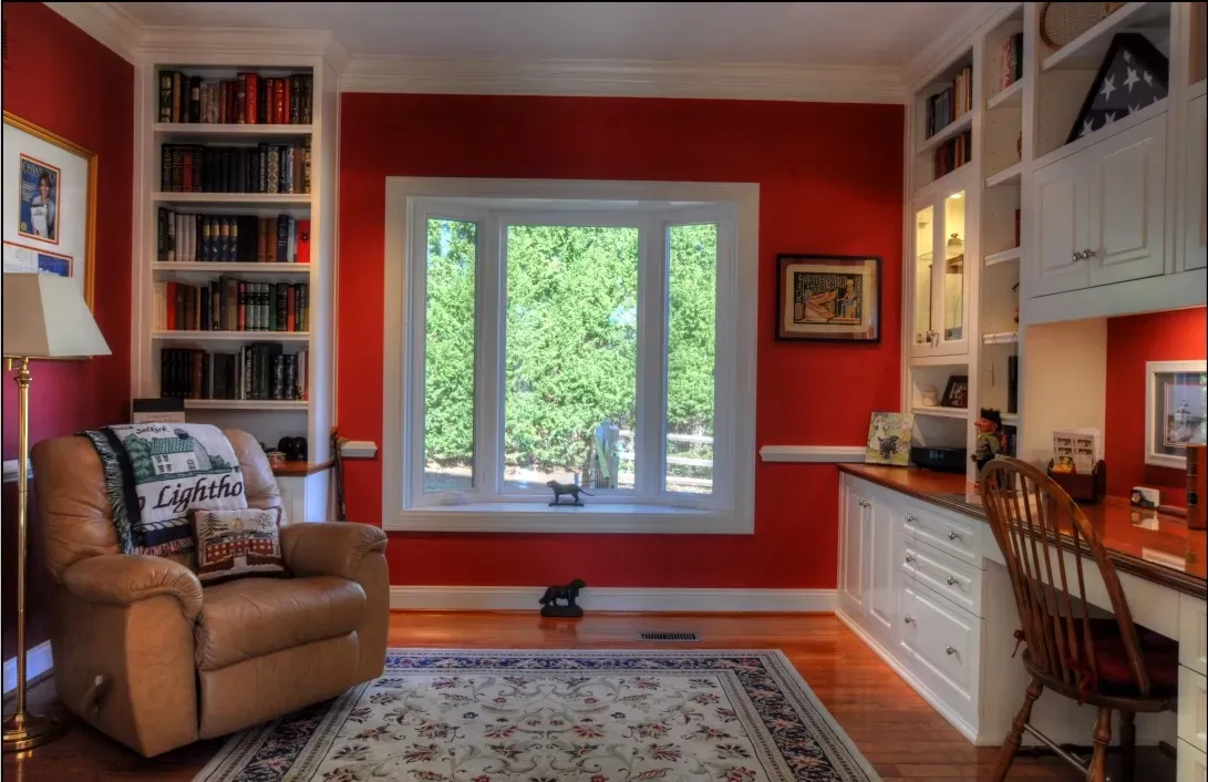 A living room with red walls and white cabinets