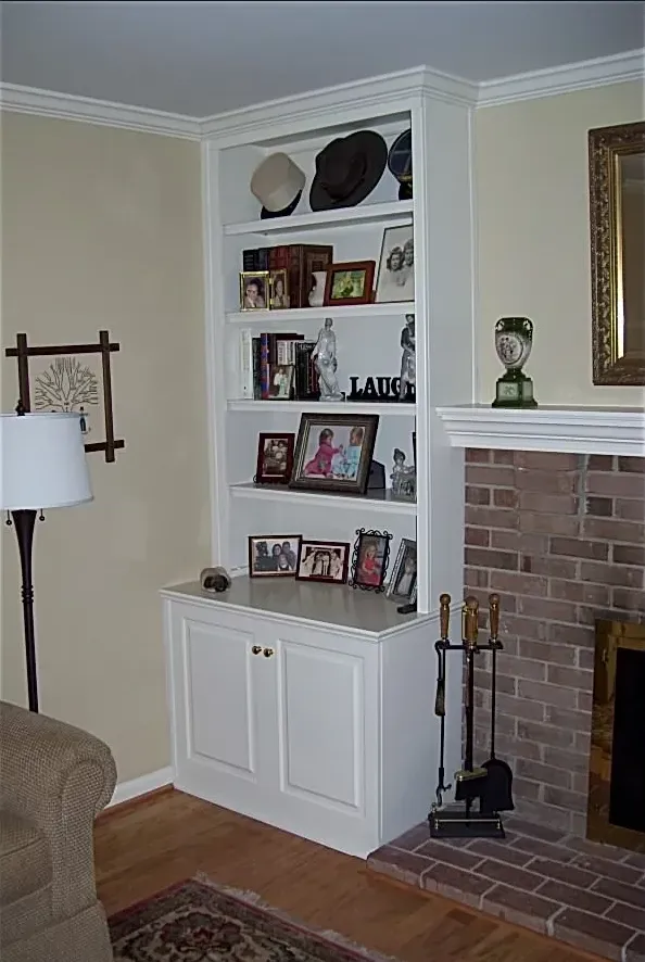 A living room with a fireplace and a shelf with pictures on it