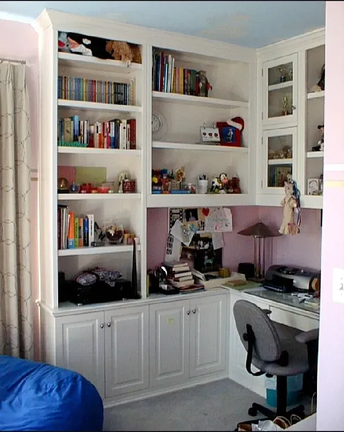 A room with a desk and shelves filled with books
