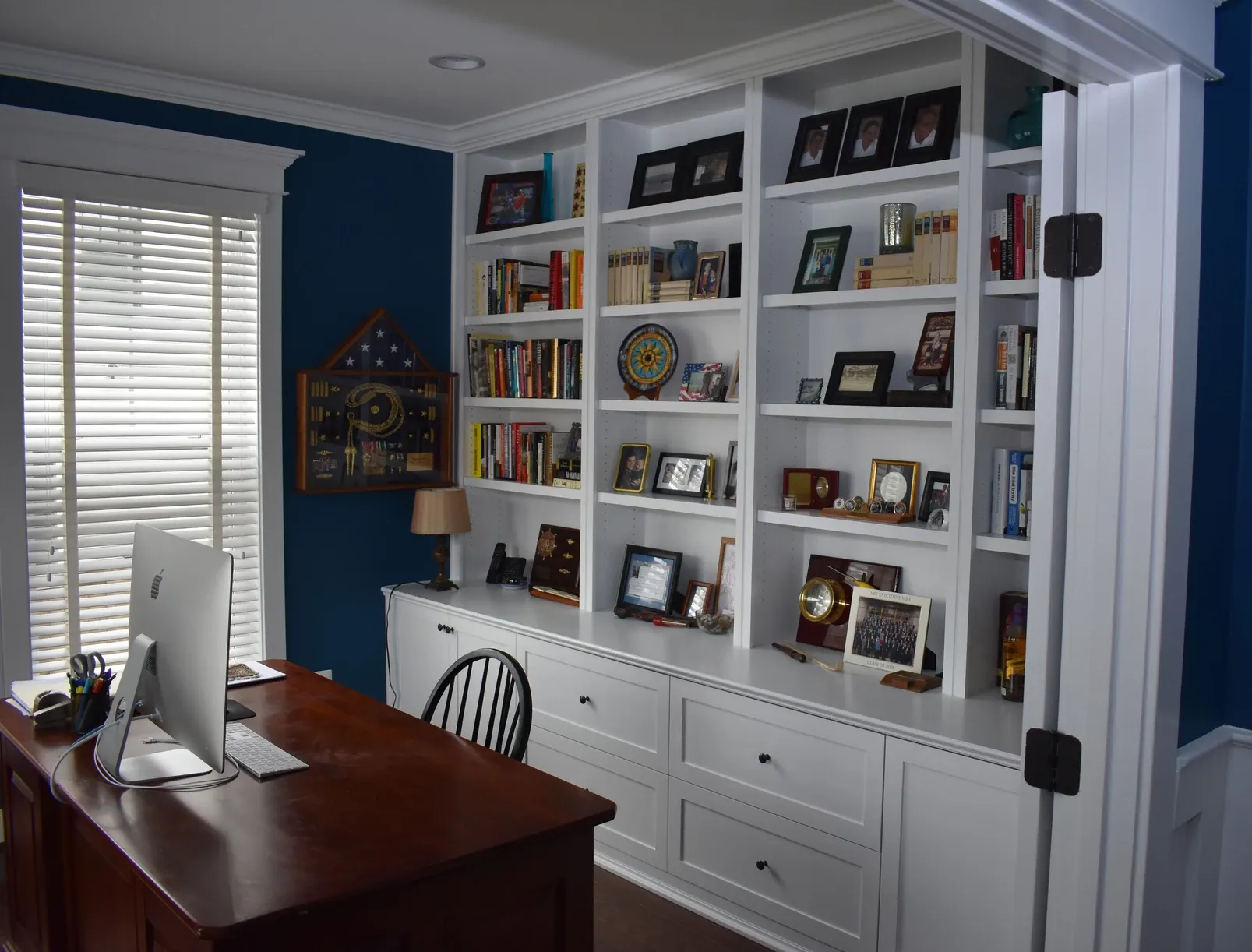 A home office with a desk and shelves filled with pictures