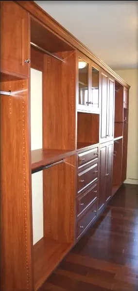 A walk in closet with wooden cabinets and drawers