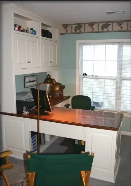 A desk with a computer and a chair in front of a window