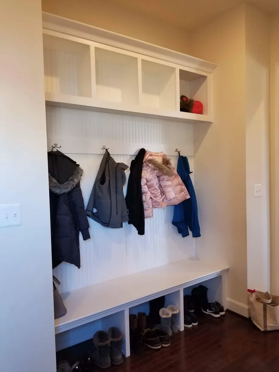 A hallway with a bench and coats hanging on the wall