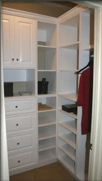 A walk in closet with lots of shelves and drawers