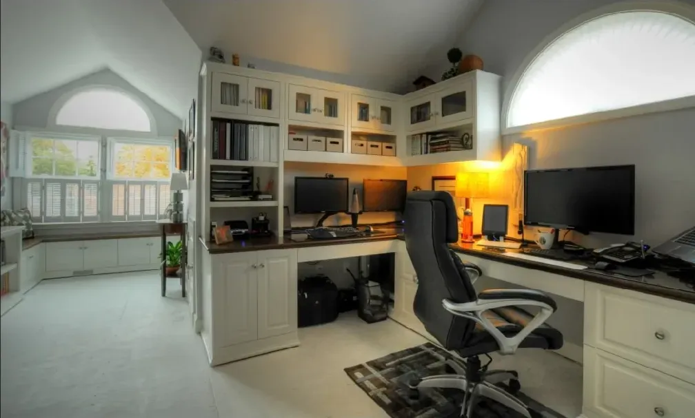 A home office with two desks and two computer monitors