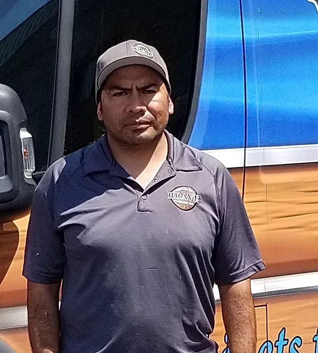 A man is standing in front of a blue van.