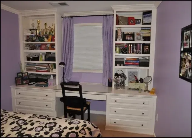 A bedroom with purple walls and a desk and shelves