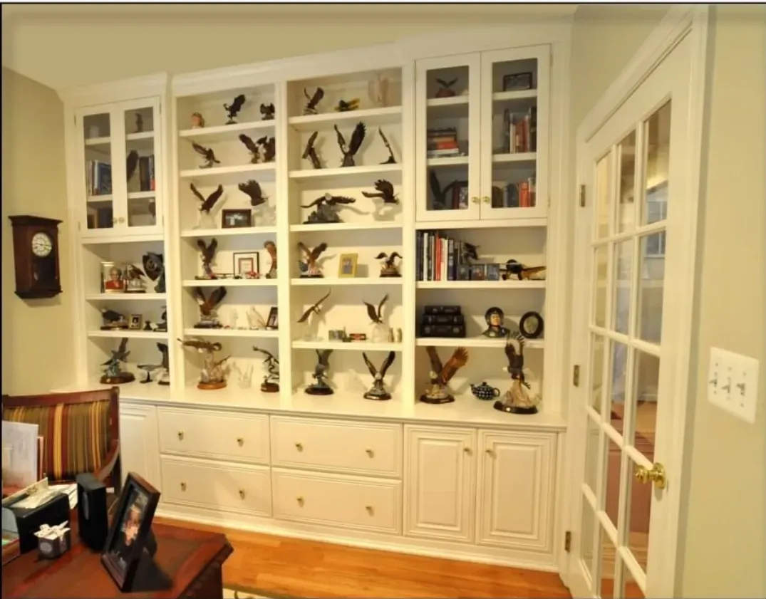 A living room with lots of shelves and a clock on the wall