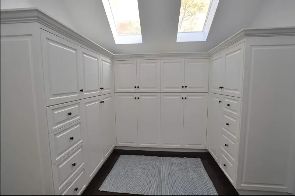 A walk in closet with lots of white cabinets and drawers